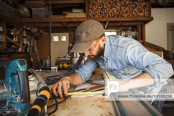 Seriöser Handwerker misst Holzkunst in der Werkstatt