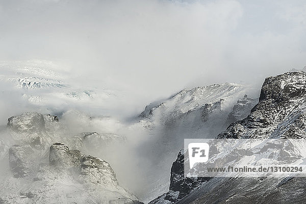 Hochwinkelansicht von schneebedeckten Bergen gegen bewölkten Himmel bei Nebel