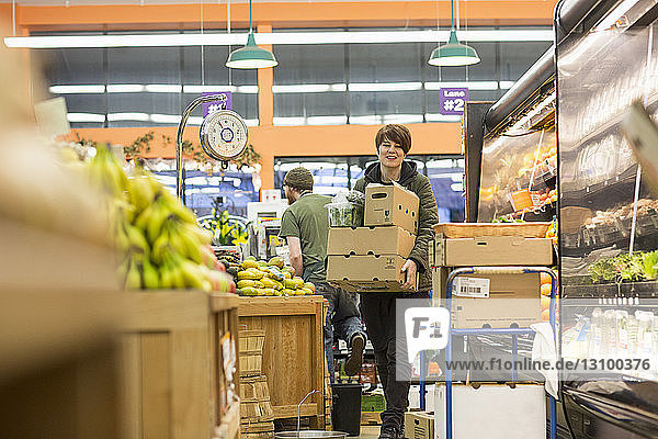 Arbeitnehmerin  die bei der Arbeit im Supermarkt Kartons trägt