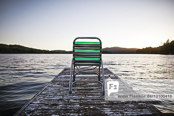Empty deck chair on jetty by lake