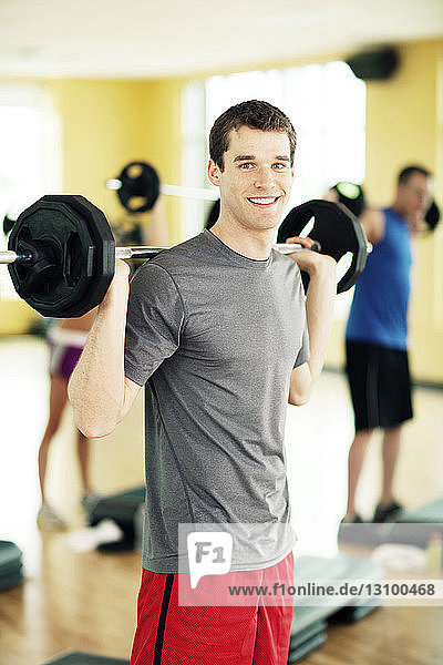 Portrait of happy male athlete lifting barbell in gym