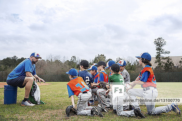Side view of coach talking to baseball team on field