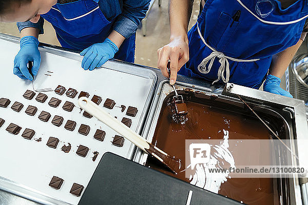 Hochwinkelaufnahme von Mitarbeitern  die in der Fabrik Schokolade zubereiten