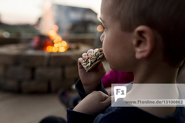 Junge isst smore im Hof mit Feuergrube im Hintergrund