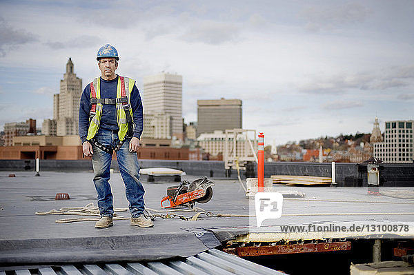 Portrait of male worker standing on building against cloudy sky