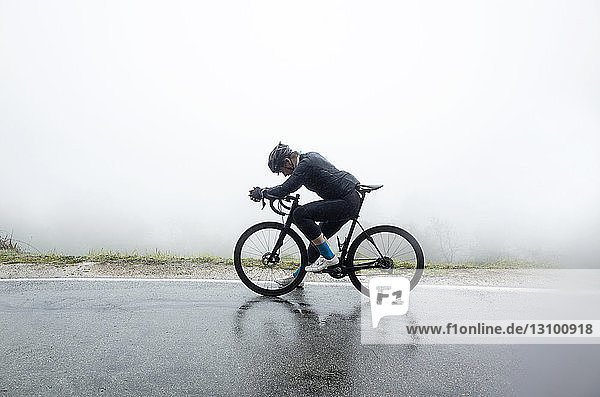 Mann entspannt sich auf dem Fahrrad auf nasser Straße bei nebligem Wetter