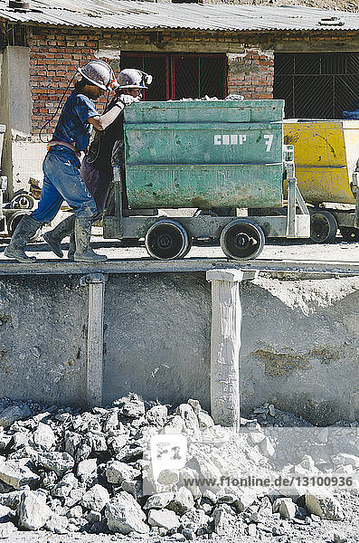 Arbeiterinnen schieben Container auf der Baustelle