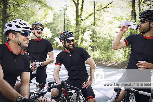 Happy male cyclists relaxing on road