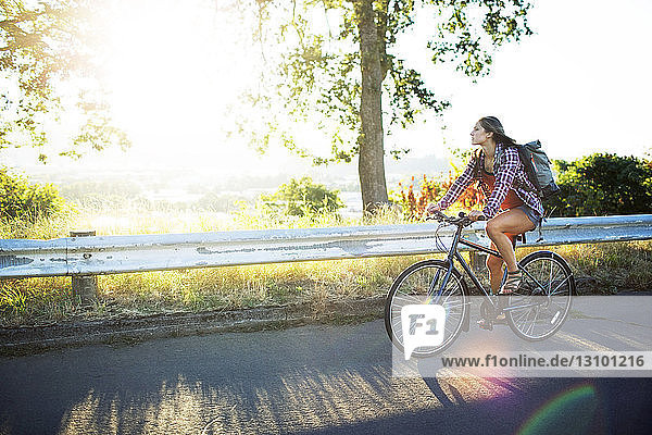 Young woman riding bicycle on road during summer