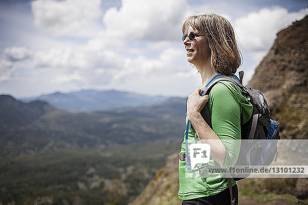 Woman carrying backpack while standing on mountain