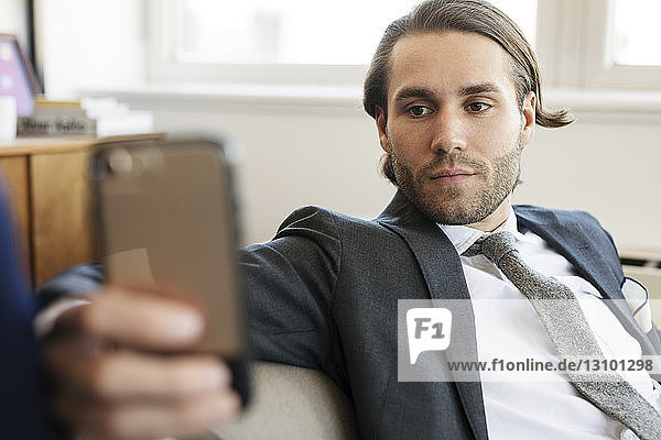 Businessman using mobile phone while sitting on sofa at home