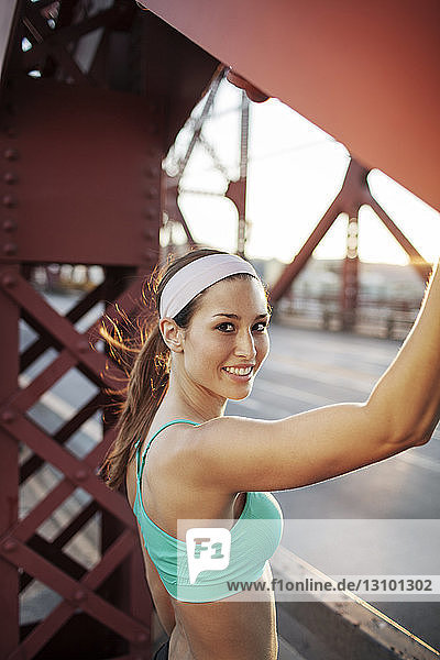 Porträt einer glücklichen jungen Frau  die auf der Brücke trainiert
