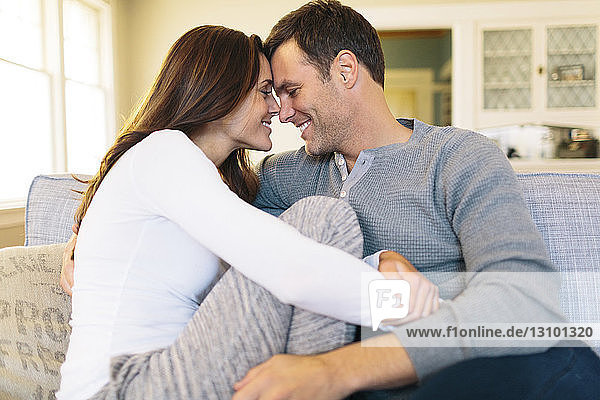 Smiling couple sitting on sofa at home