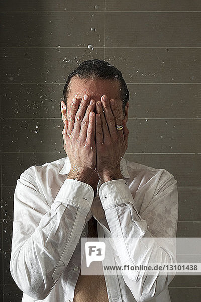 Young man taking shower in bathroom at home