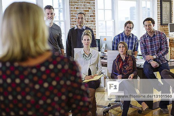 Business people listening to businesswoman explaining in meeting at office