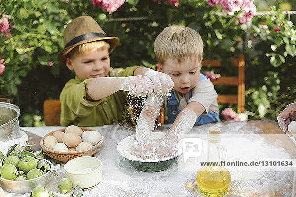 High angle view of brothers preparing food on table in yard