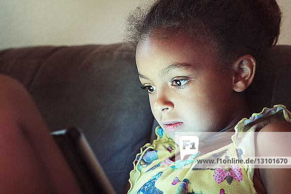 Nahaufnahme eines Mädchens  das einen Tablet-Computer benutzt  während es zu Hause auf dem Sofa sitzt