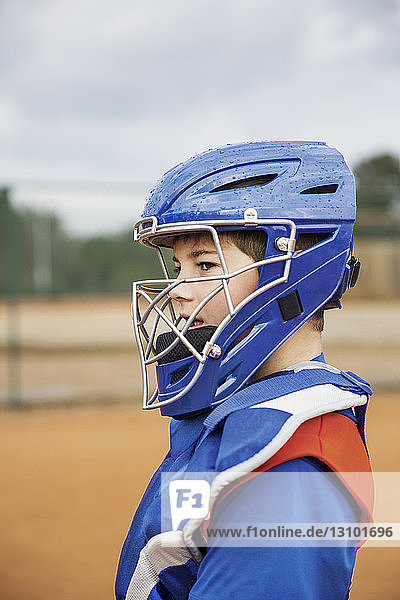 Side view of baseball catcher standing on field