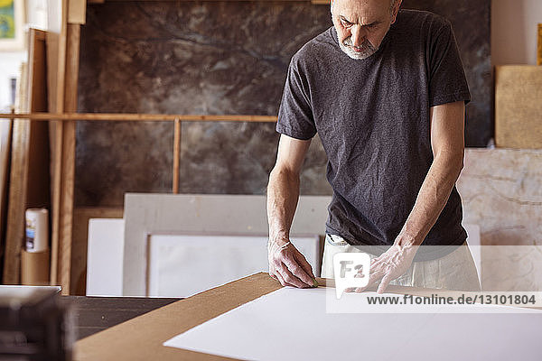 Male artist rubbing on paper in workshop
