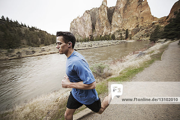 Determined man jogging on footpath by lake