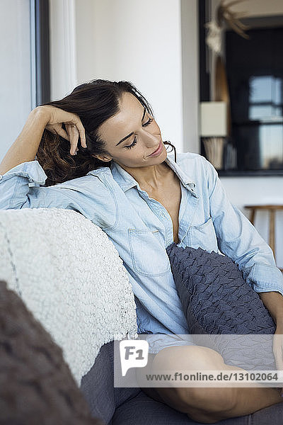 Woman with eyes closed relaxing on sofa