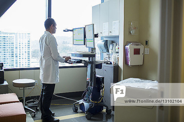 Männlicher Arzt am Desktop-Computer auf der Krankenstation