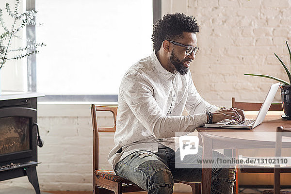 Happy young man using laptop at home