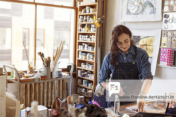 Smiling artist painting in workshop