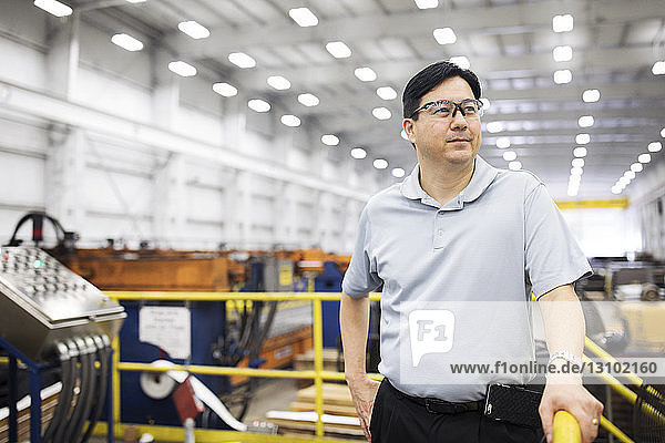 Zuversichtlicher Vorgesetzter schaut weg  während er in der Fabrik der Stahlindustrie steht