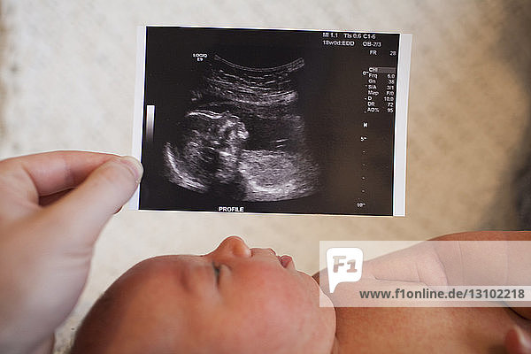Cropped hand of mother holding ultrasound report by son