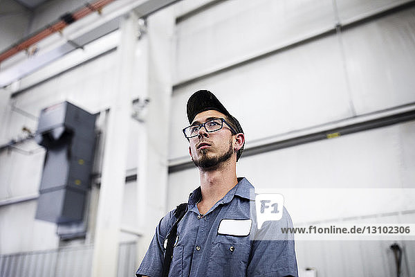 Niedriger Blickwinkel eines Arbeiters  der bei der Arbeit im Metall-Stahlwerk wegschaut