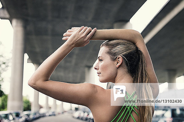 Rückansicht einer selbstbewussten Sportlerin  die ihre Arme unter der Brücke ausstreckt