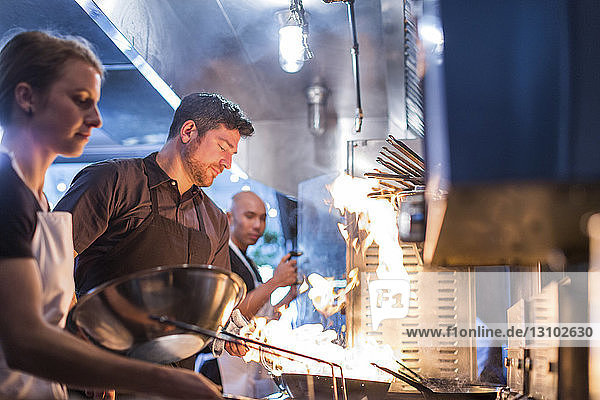 Chefs preparing food in flames at restaurant kitchen