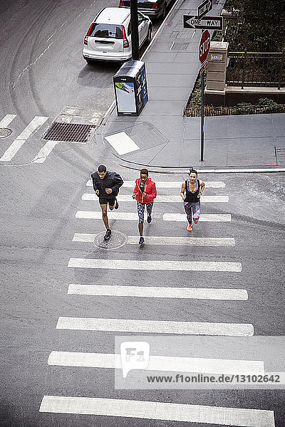 Overhead view of athletes running on zebra crossing on city street