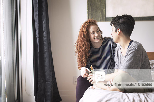 Happy couple talking while sitting on bed at home