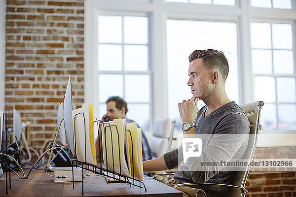 Male colleagues working at desk in office