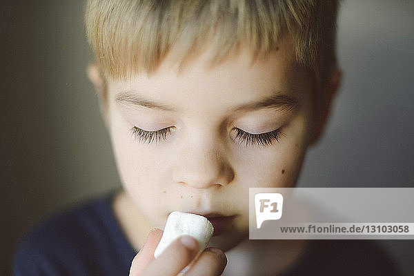 Nahaufnahme eines Jungen mit geschlossenen Augen beim Marshmallow-Essen zu Hause