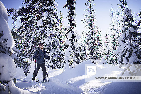 Junger Mann auf Schneeschuhen durch den Wald