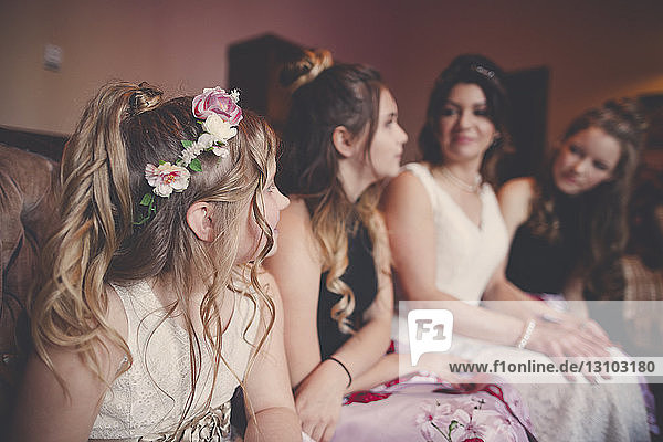 Braut mit Brautjungfern und Blumenmädchen zu Hause sitzend