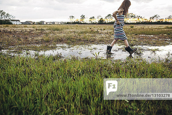Seitenansicht eines unordentlichen Mädchens  das auf einem nassen Feld läuft