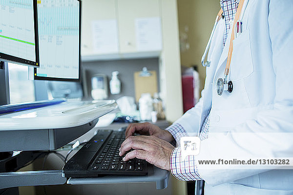 Mittelsektion eines männlichen Arztes am Desktop-Computer auf der Krankenhausstation