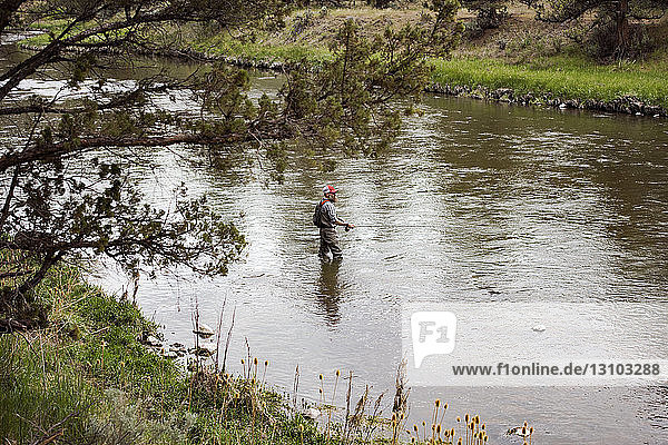 Hochwinkelaufnahme eines erwachsenen Mannes  der im Fluss fischt