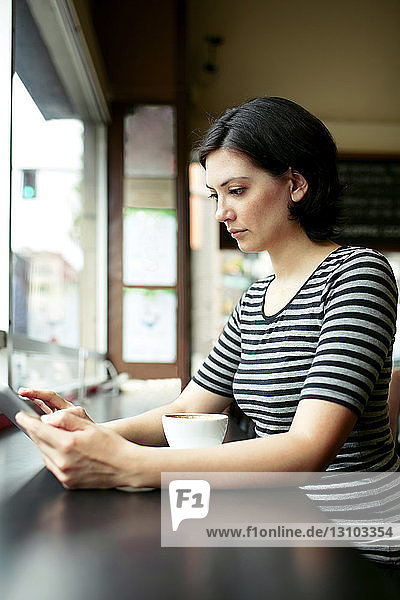 Junge Frau benutzt Tablet-Computer am Café-Tisch