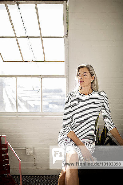 Woman with legs crossed at knee sitting at home