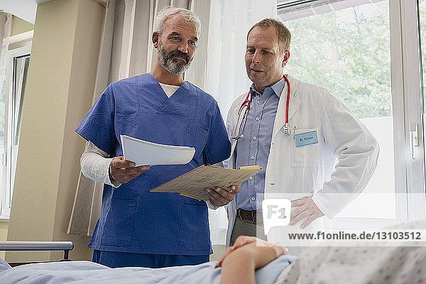 Männliche Ärzte bei der Visite im Krankenhauszimmer