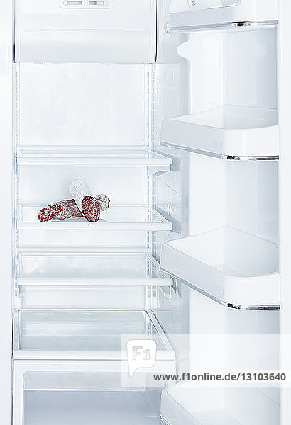 Salami in open  empty white refrigerator