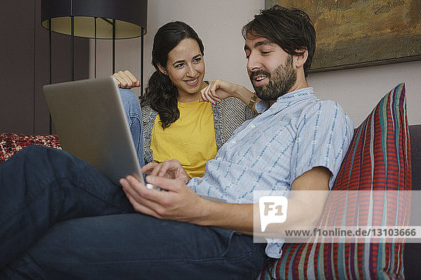 Couple using laptop on living room sofa
