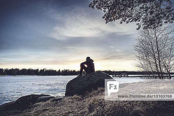 Mann sitzt auf einem Felsen mit Blick auf den See Nydala  Umea  Schweden
