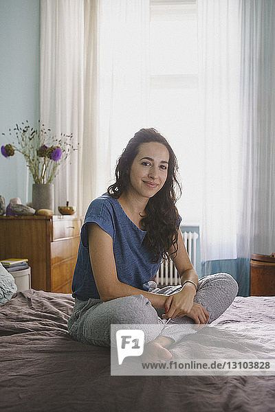 Porträt lächelnde Frau auf Bett sitzend