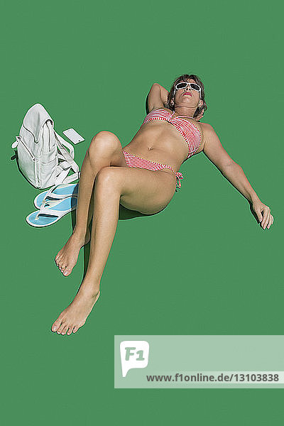 Frau im Bikini beim Sonnenbaden auf grünem Hintergrund